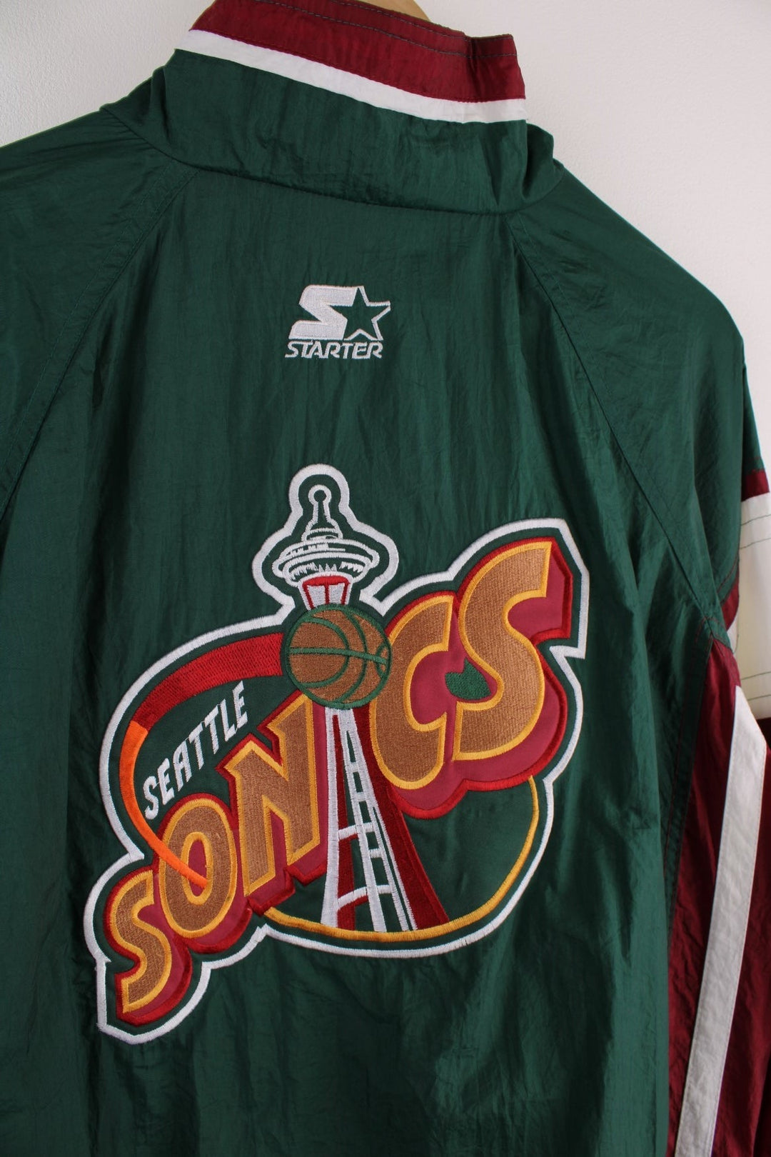 Seattle SuperSonics NLF jacket in  with burgundy and white panels, two pockets, an embroidered team logo on the back and NBA logo on the sleeve.