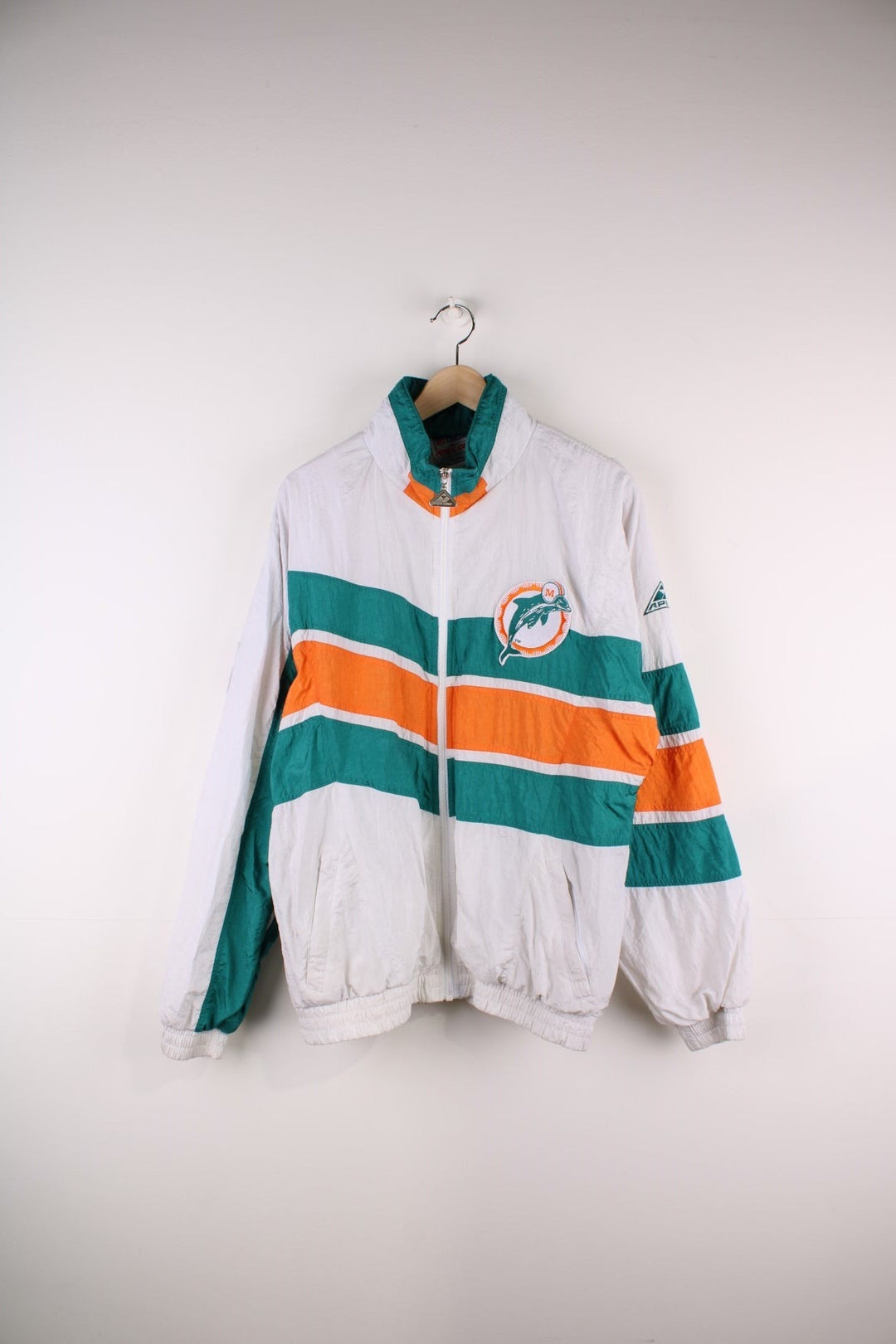 Miami Dolphins NFL Jacket in white with turquoise and orange stripes, the dolphin logo on the chest and script on the back, and Apex and NFL logos on each sleeve.