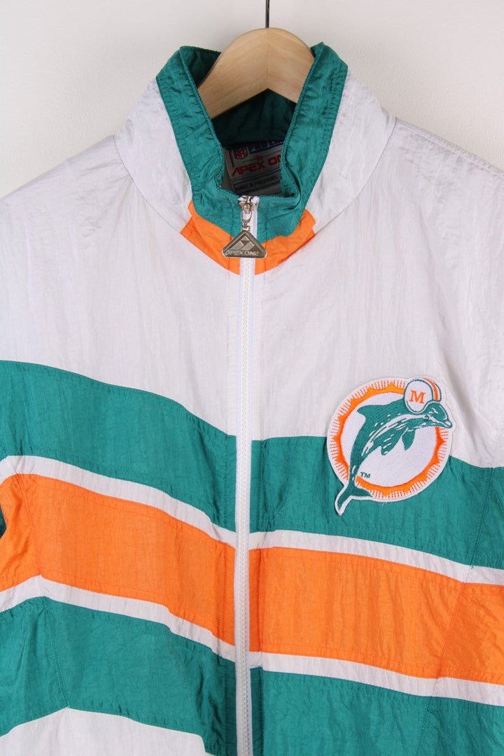 Miami Dolphins NFL Jacket in white with turquoise and orange stripes, the dolphin logo on the chest and script on the back, and Apex and NFL logos on each sleeve.