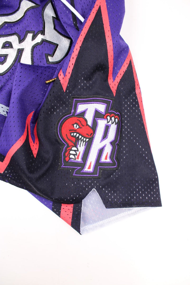 Toronto Raptors Basketball Shorts in a purple, silver, black and red colourway, has a adjustable waist with drawstrings, multiple pockets, and the logos and spell out embroidered on the front.