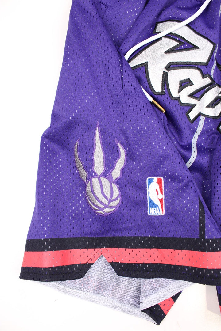 Toronto Raptors Basketball Shorts in a purple, silver, black and red colourway, has a adjustable waist with drawstrings, multiple pockets, and the logos and spell out embroidered on the front.