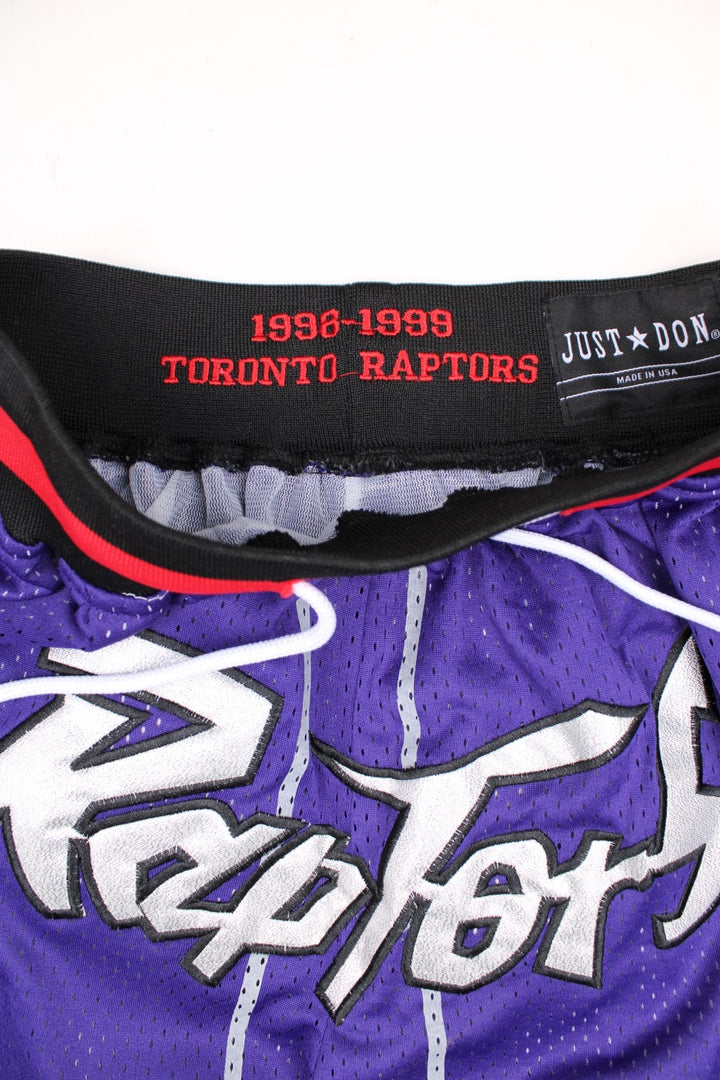 Toronto Raptors Basketball Shorts in a purple, silver, black and red colourway, has a adjustable waist with drawstrings, multiple pockets, and the logos and spell out embroidered on the front.