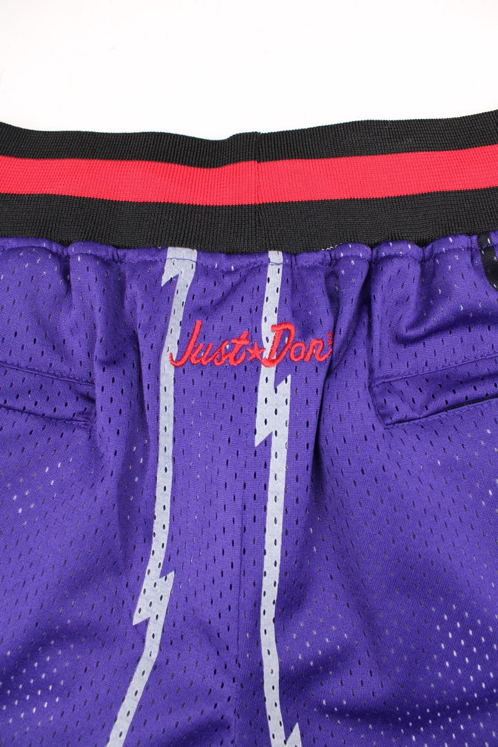 Toronto Raptors Basketball Shorts in a purple, silver, black and red colourway, has a adjustable waist with drawstrings, multiple pockets, and the logos and spell out embroidered on the front.