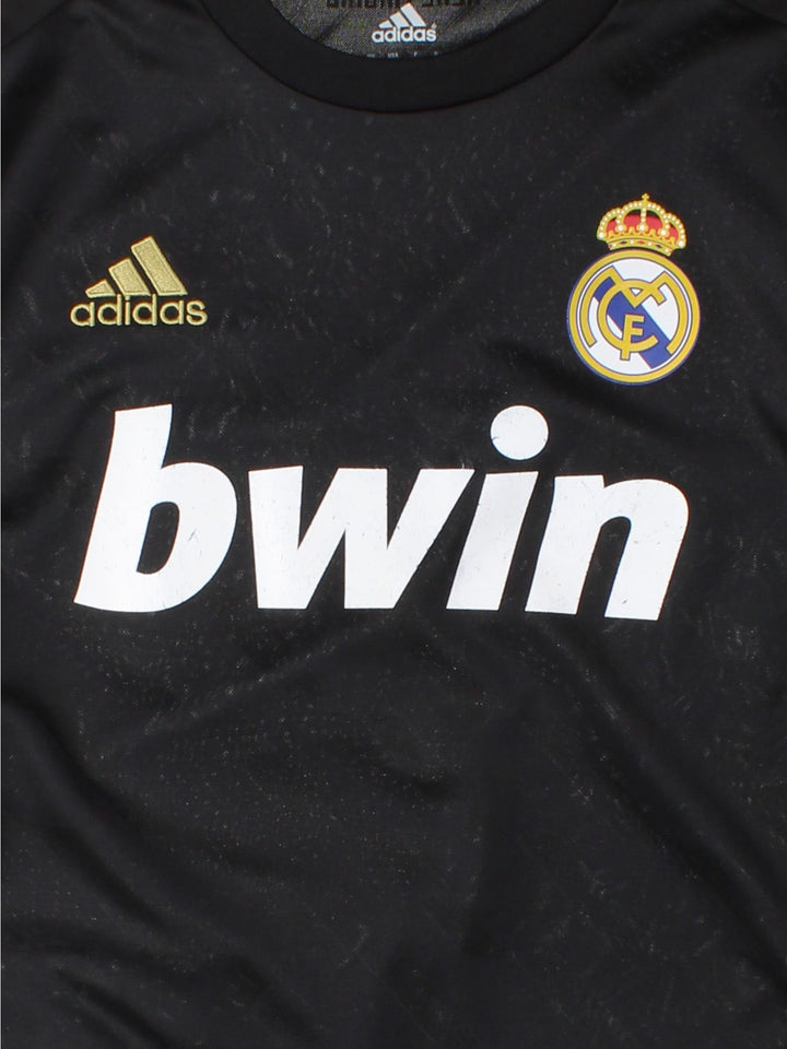 Real Madrid 2011/12 Adidas football shirt in the away kit black with gold three stripe detailing, printed and embroidered logos, and a badge on the front.