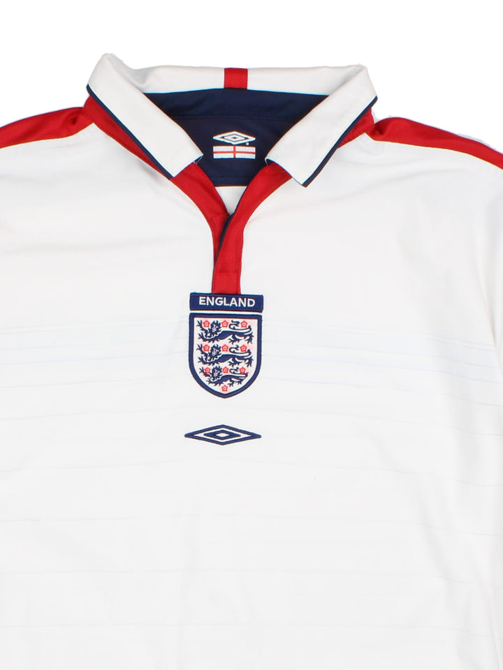 England 2003/05 Umbro home kit reversible football shirt in white with blue stripes and navy blue collar and piping on one side, red on the other. 2 snap closure at the neck, and a logo and badge on the front on both sides.