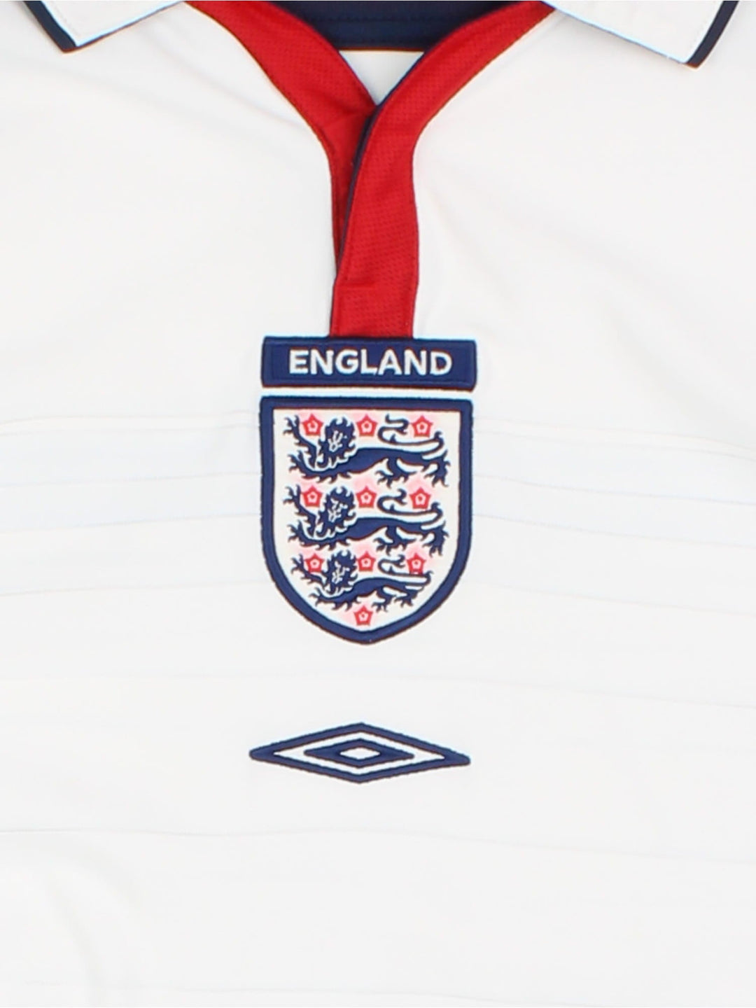 England 2003/05 Umbro home kit reversible football shirt in white with blue stripes and navy blue collar and piping on one side, red on the other. 2 snap closure at the neck, and a logo and badge on the front on both sides.