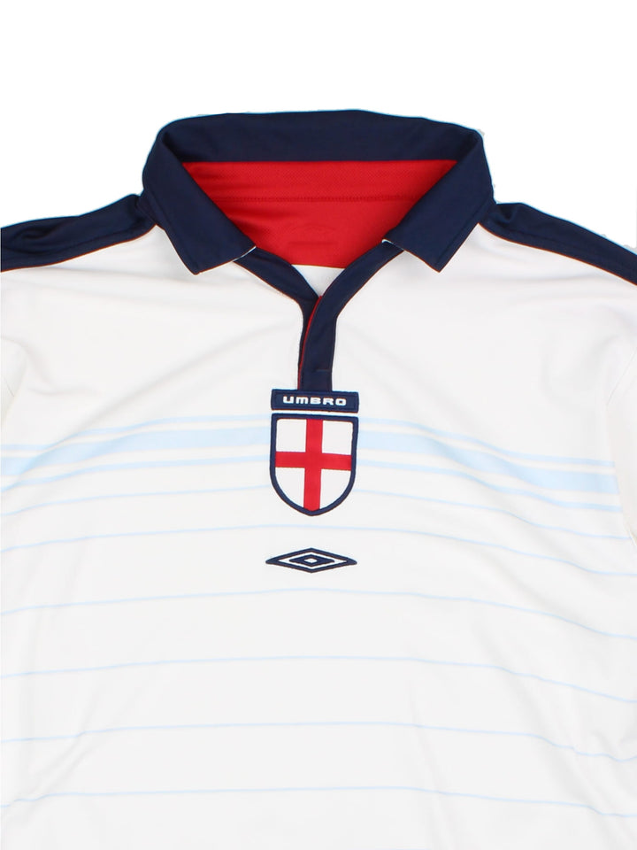 England 2003/05 Umbro home kit reversible football shirt in white with blue stripes and navy blue collar and piping on one side, red on the other. 2 snap closure at the neck, and a logo and badge on the front on both sides.