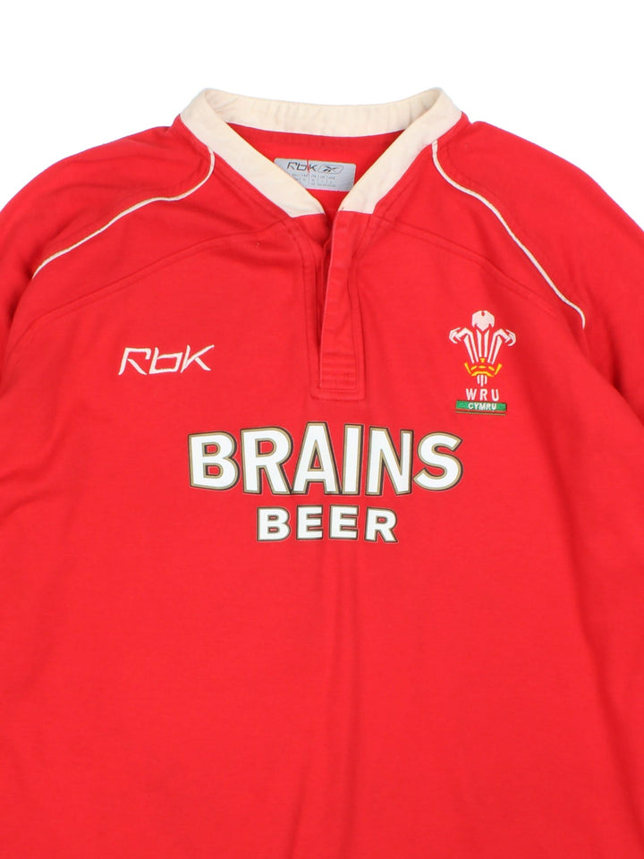 Reebok 2007/08 Wales Rugby Union shirt in red with 2 buttons at the collar, white piping, and printed and embroidered team and sponsor logos on the front.