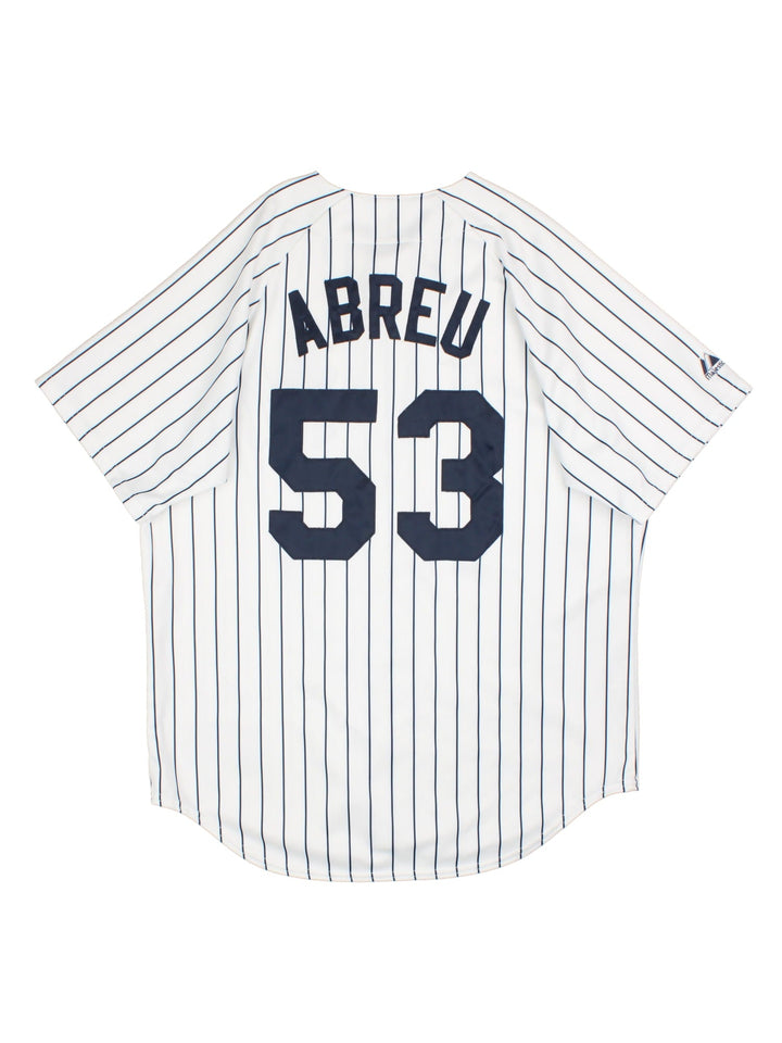 New York Yankees Majestic MLB Jersey in the white home kit colourway, features classic logo on front and traditional blue stripe detailing, button down front, has the player name ABREU and number 53 on the back.