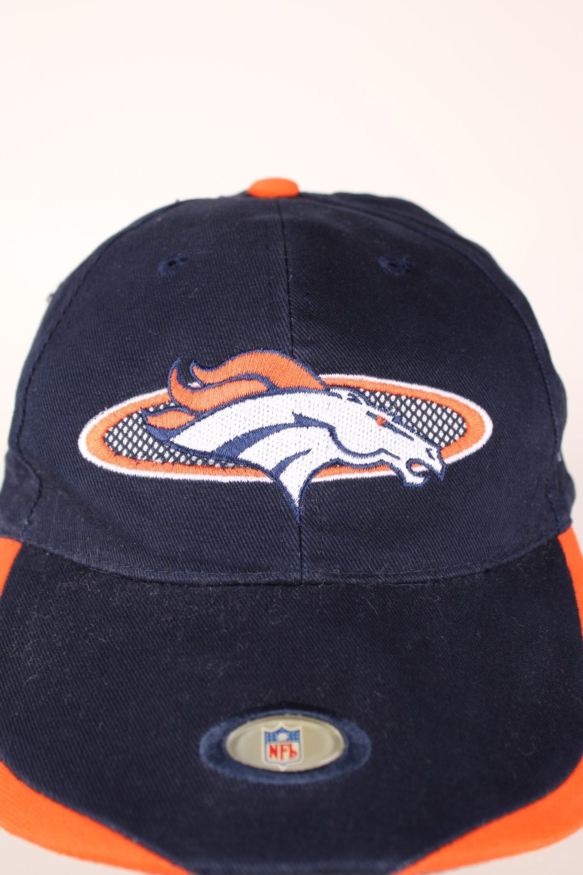 NFL Denver Broncos baseball cap in navy blue and orange with embroidered logo and adjustable velcro strap. 