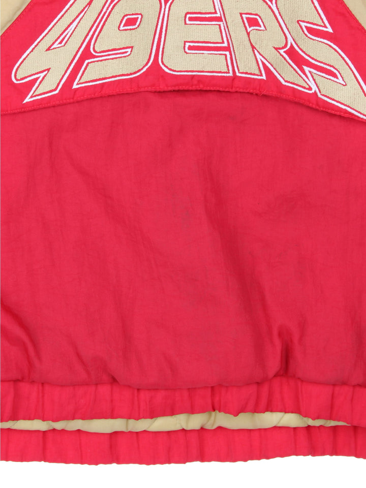 San Francisco 49ers, NFL pro sport jacket in a red colourway with beige and white side panels. Zip closure and hood, with team logos on the front, sleeve and back.