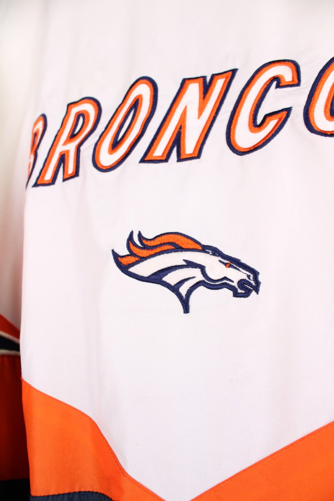 Broncos pro sport jacket in white, orange and navy. Zip closure with team logos embroidered on the front and back.