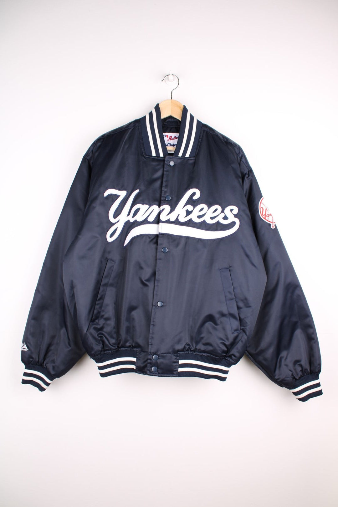 NY Yankees vintage pro sport bomber jacket in navy blue satin with white stripe detail. Snap fastener closure, with team logos embroidered on the front and sleeve.