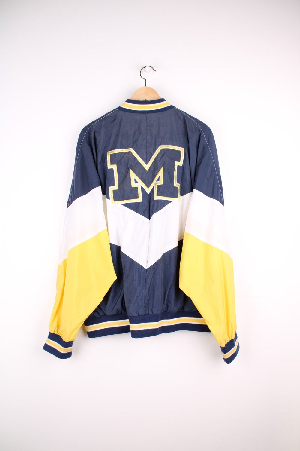 Michican Wolverines pro sport jacket in a navy colourway with white and yellow panels. Zip closure with team logos embroidered on the front and back.