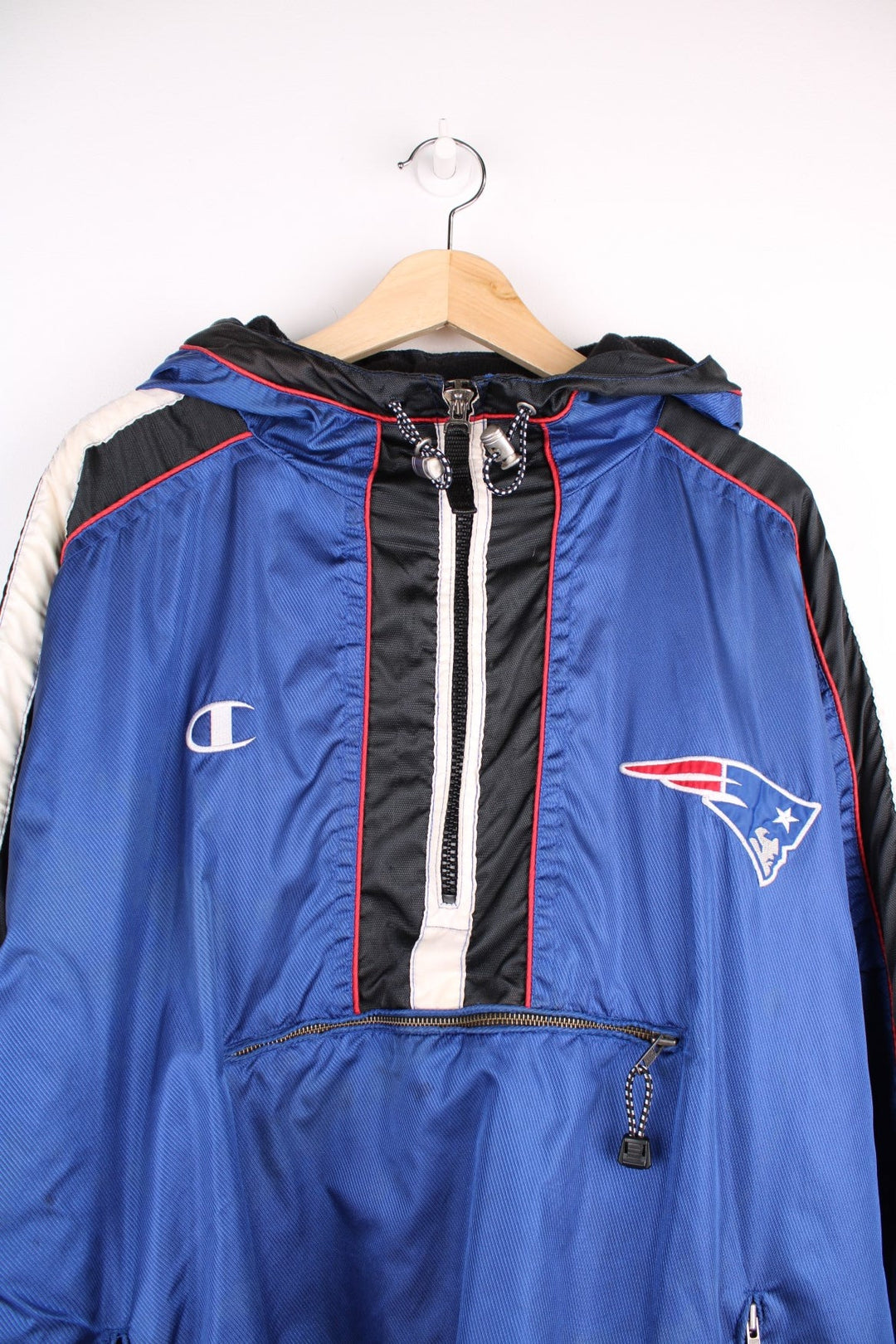 New England Patriots pro sport jacket in a blue colourway with white and red detail. Zip closure and hood with team logos embroidered on the front and back.