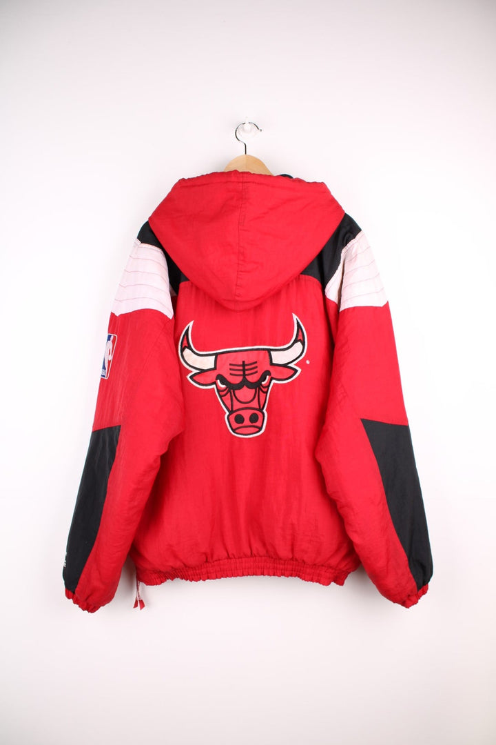 Chicago Bulls NBA pro sport jacket in a red colourway with white and black panels. Zip closure and hood with team logos embroidered on the front and back.