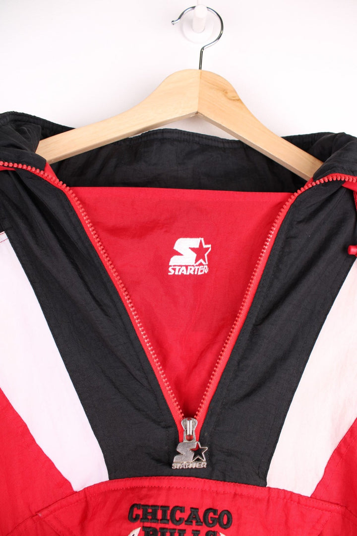 Chicago Bulls NBA pro sport jacket in a red colourway with white and black panels. Zip closure and hood with team logos embroidered on the front and back.