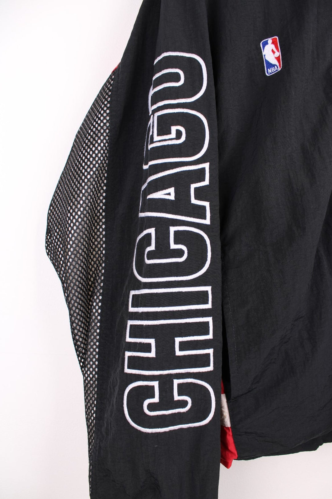 Chicago Bulls NBA pro sport jacket in a black colourway with red side panels. Full zip closure with team logos embroidered on the front and back.