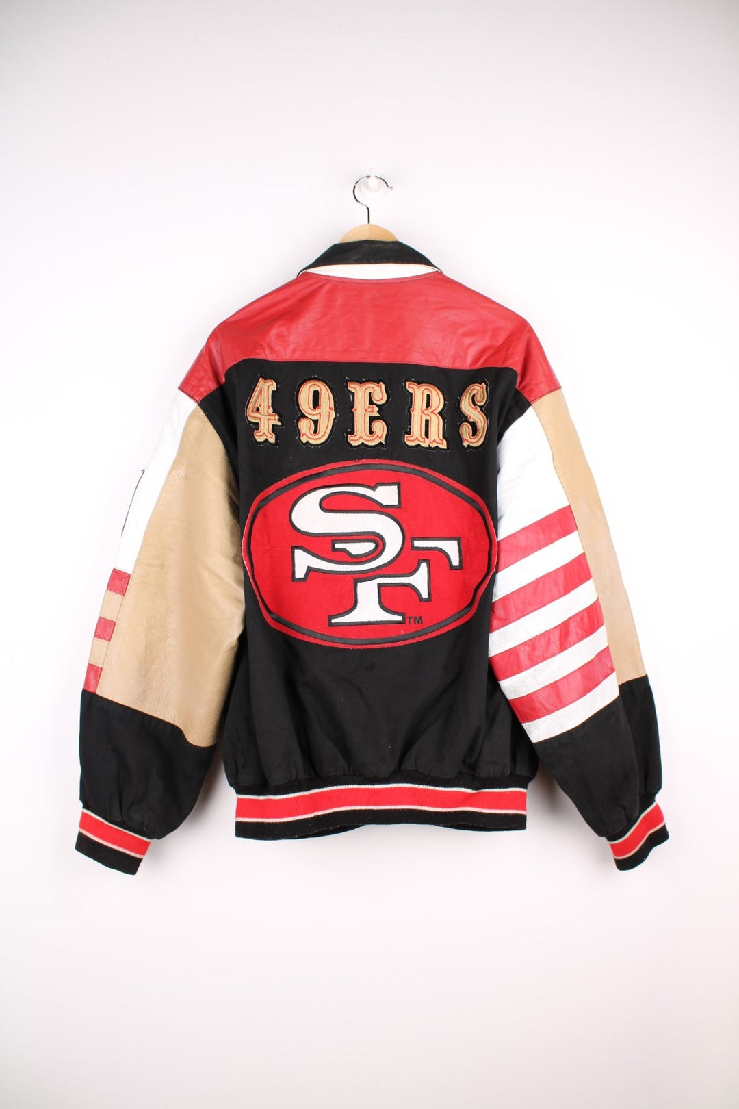 San Francisco 49s, NFL, Jeff Hamilton bomber-style pro sport jacket in a black colourway with white, red and tan detail. Zip closure with team logos embroidered on the front and back.