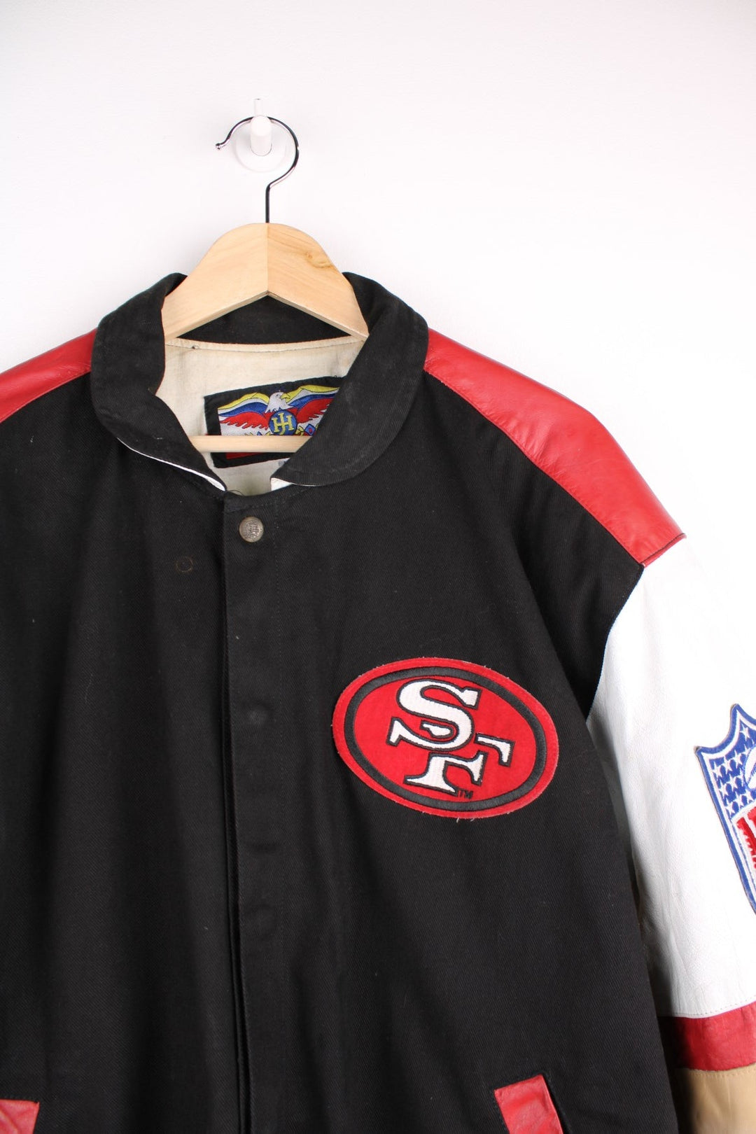 San Francisco 49s, NFL, Jeff Hamilton bomber-style pro sport jacket in a black colourway with white, red and tan detail. Zip closure with team logos embroidered on the front and back.