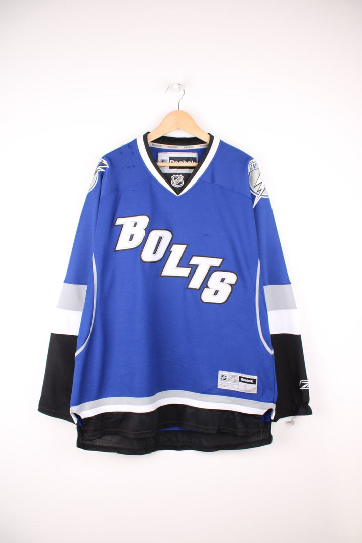 Tampa Bay Lightning Reebok, NHL Hockey Jersey. Features embroidered "BOLTS" across the front and badges on the sleeves. 