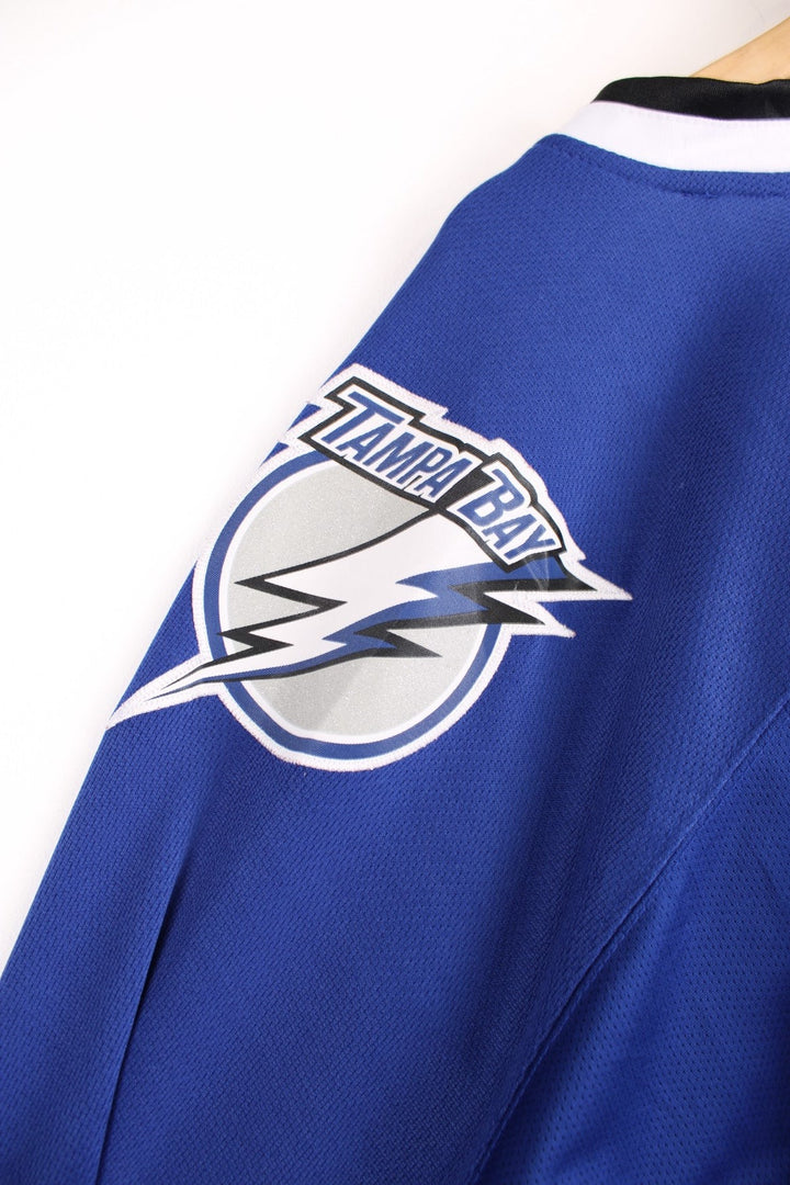 Tampa Bay Lightning Reebok, NHL Hockey Jersey. Features embroidered "BOLTS" across the front and badges on the sleeves. 