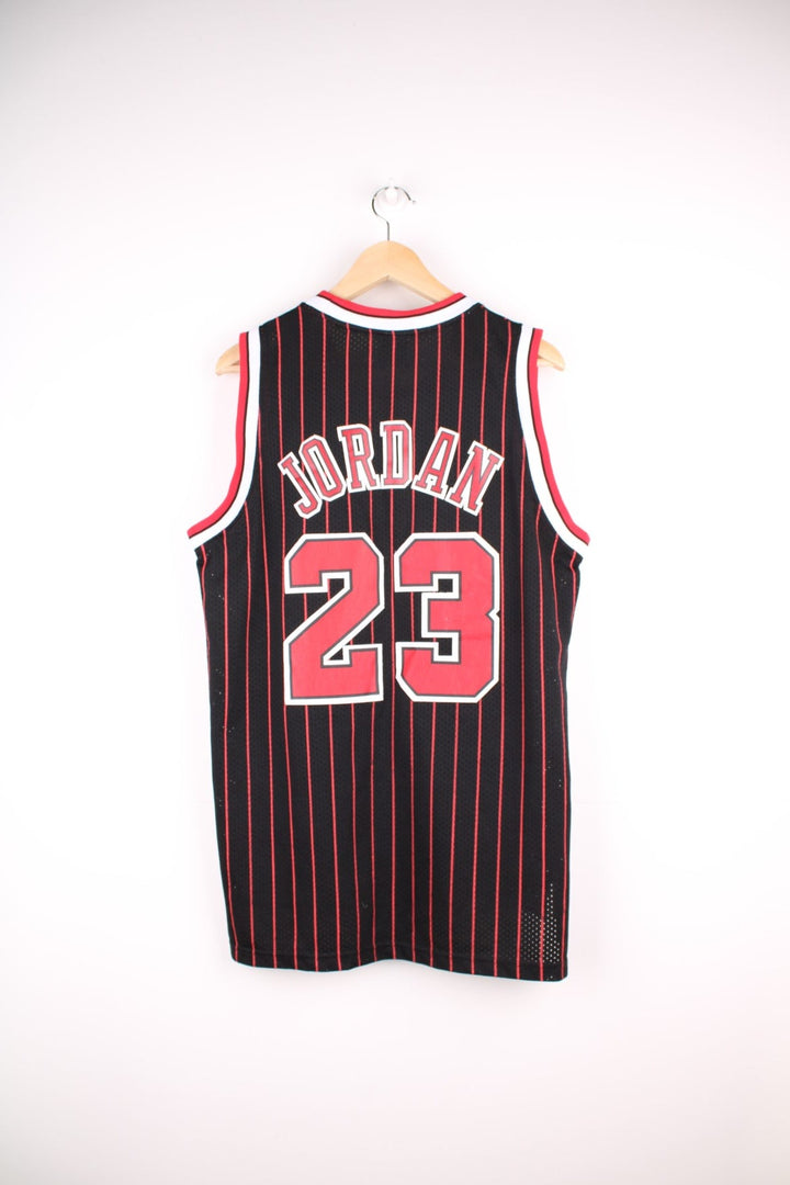 Chicago Bulls NBA jersey in black with red stripes, white accents, multiple embroidered logos, and no.23 Jordan on the front and back.