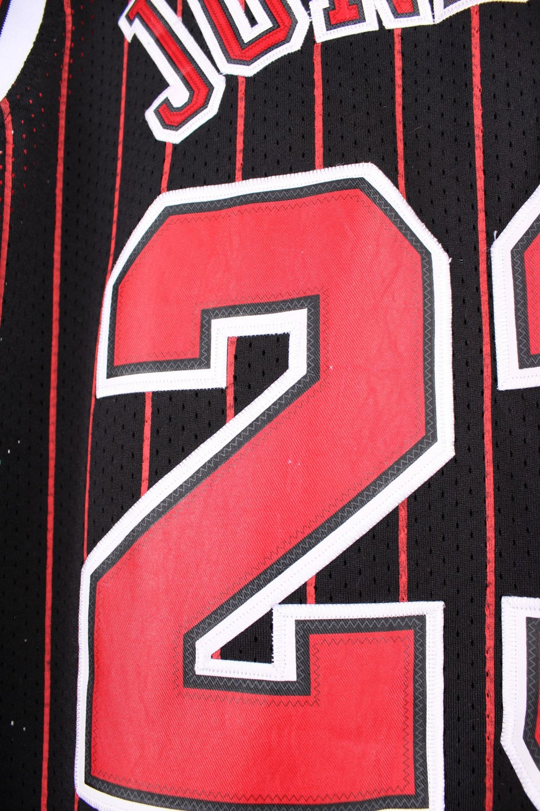 Chicago Bulls NBA jersey in black with red stripes, white accents, multiple embroidered logos, and no.23 Jordan on the front and back.