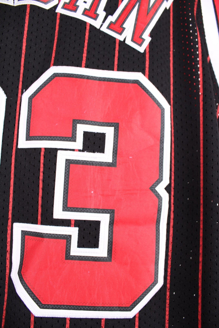 Chicago Bulls NBA jersey in black with red stripes, white accents, multiple embroidered logos, and no.23 Jordan on the front and back.