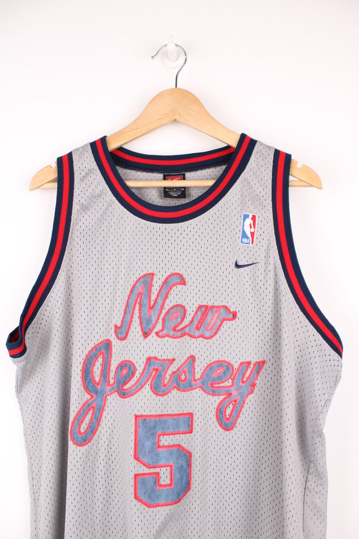 New Jersey Nets, Kidd #5 Nike NBA basketball jersey in a grey, red and blue colourway. Features embroidered lettering on the front and bag, and logos on the chest.