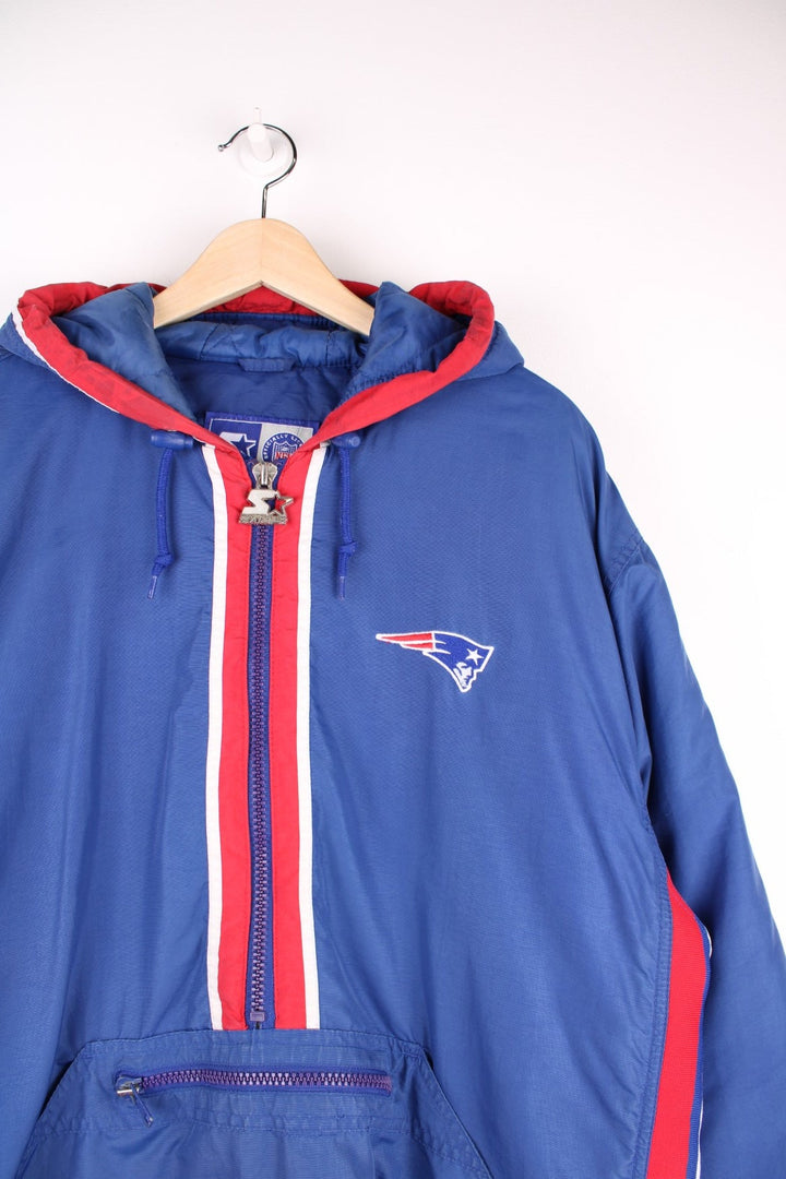 Starter NFL New England Patriots Pullover Jacket in a blue, white and red colourway, half zip up with big pouch pockets, insulated with quilted lining, hooded, and has the team logo embroidered on the front and back.