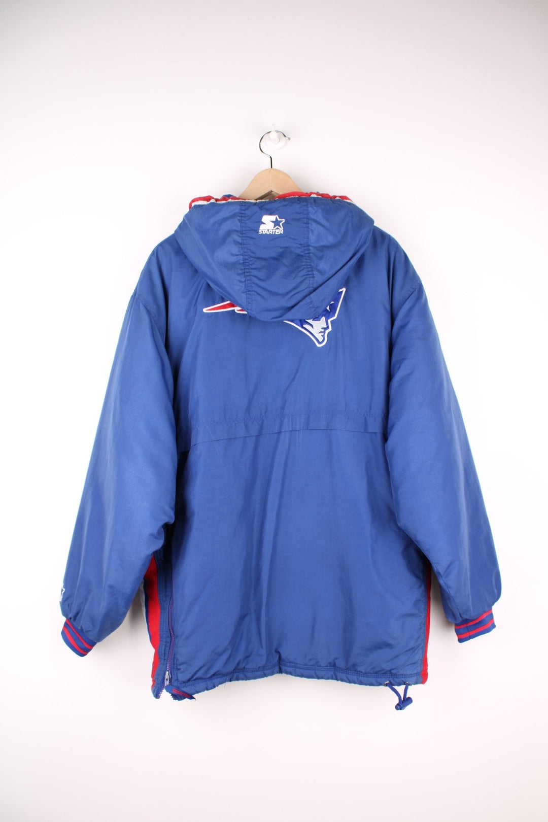 Starter NFL New England Patriots Pullover Jacket in a blue, white and red colourway, half zip up with big pouch pockets, insulated with quilted lining, hooded, and has the team logo embroidered on the front and back.