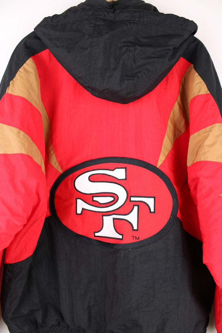 Vintage San Francisco 49ers Pro Line by Apex One Jacket in the red, black and gold team colourway, zip up with side pockets, has a detachable hood, quilted with a insulated lining, and has the logo embroidered on the front, sleeves, and back.