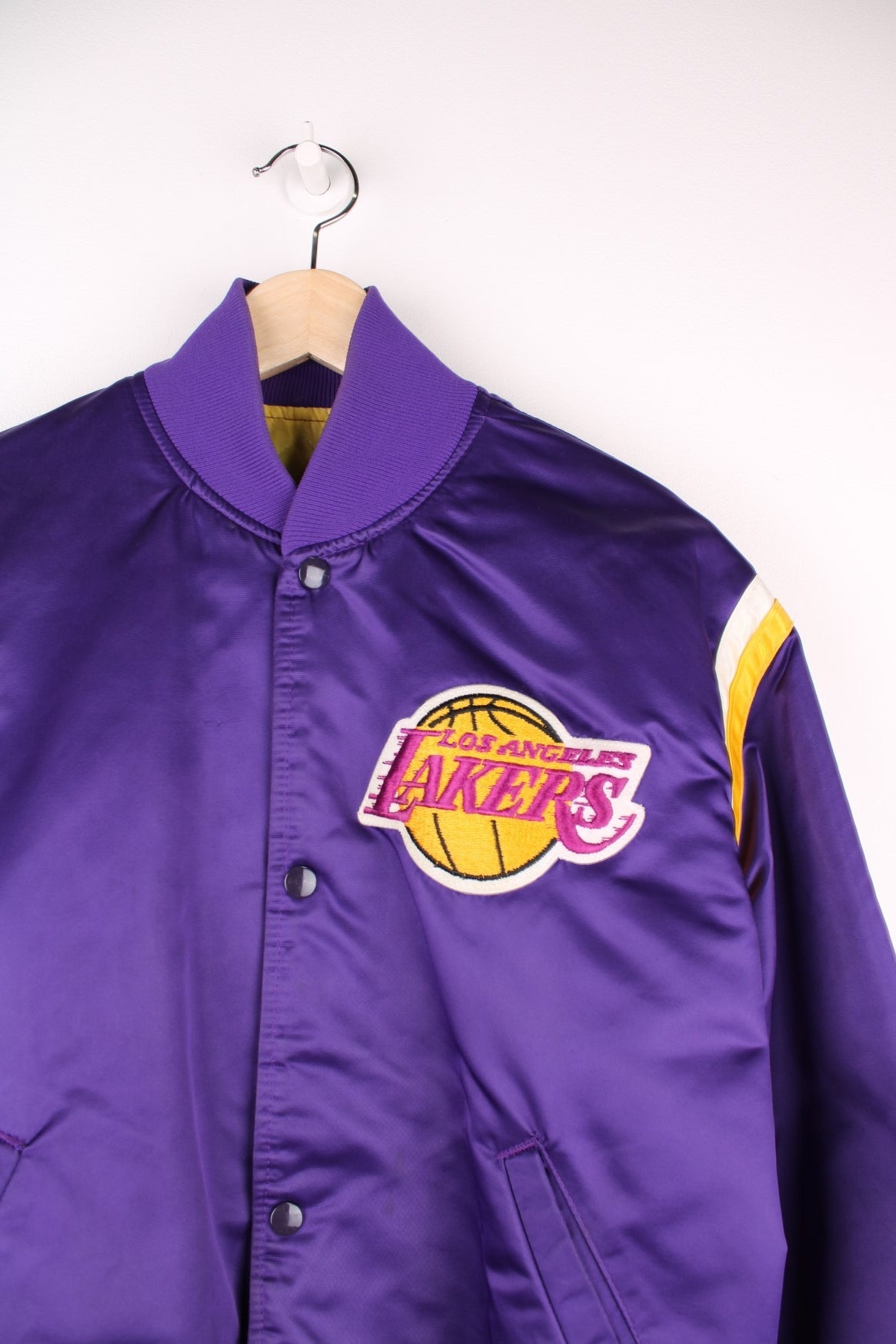 Los Angeles Lakers Starter NBA Varsity Jacket in a purple, yellow and white colourway, button up with side pockets, insulated with a quilted lining, and has the team and NBA logo embroidered on the front.