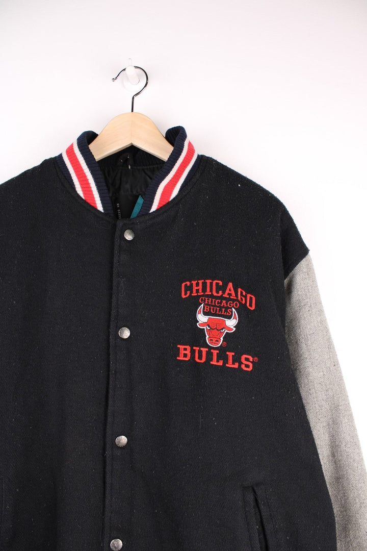 Vintage 90's Chicago Bulls Logo 7 Woolen Varsity Jacket Athletic in a black, grey and red colourway, button up with side pockets, insulated with a quilted lining, and has the team spell out and logo embroidered on the front and back.