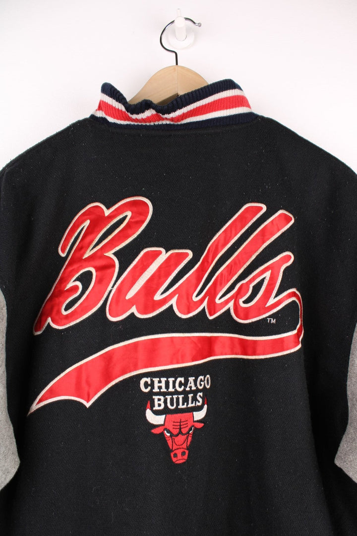 Vintage 90's Chicago Bulls Logo 7 Woolen Varsity Jacket Athletic in a black, grey and red colourway, button up with side pockets, insulated with a quilted lining, and has the team spell out and logo embroidered on the front and back.