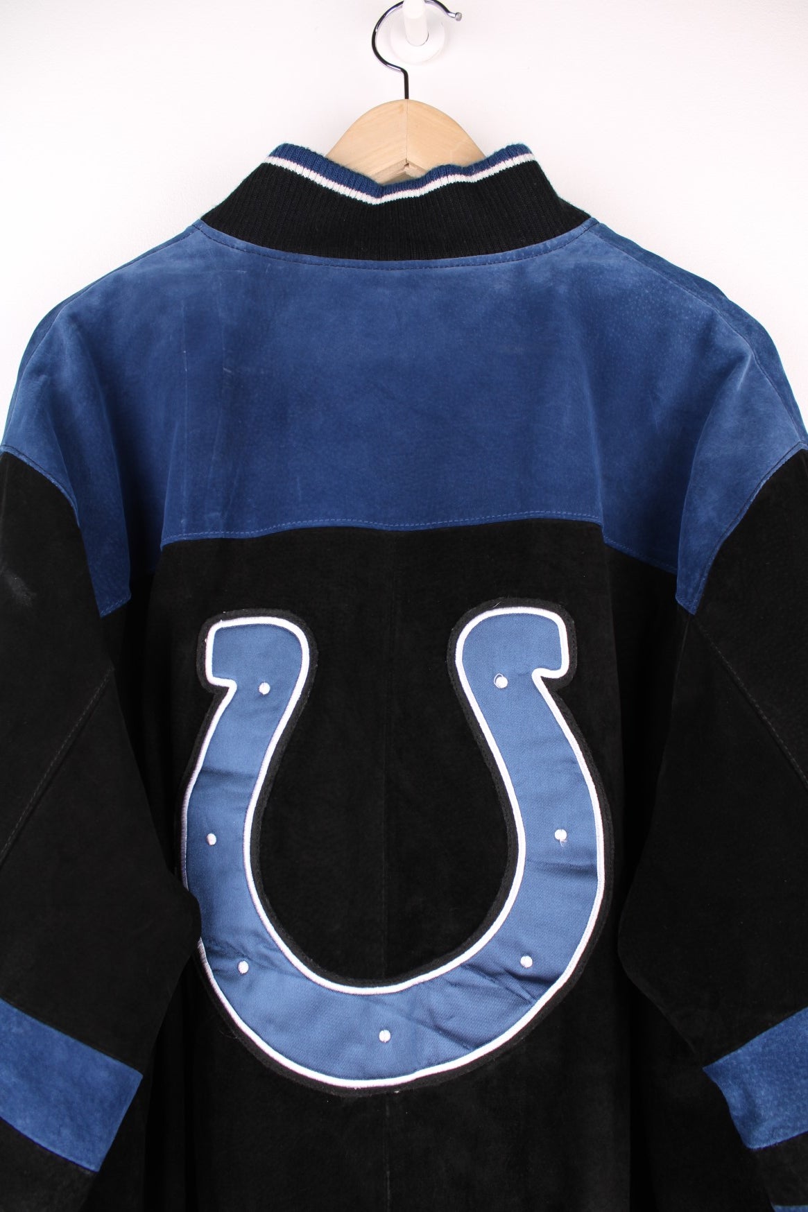 Indianapolis Colts Leather Varsity Jacket in a black and blue colourway, button up with side pockets, insulated with a quilted lining, and has the team spell out and logo embroidered on the front and back.