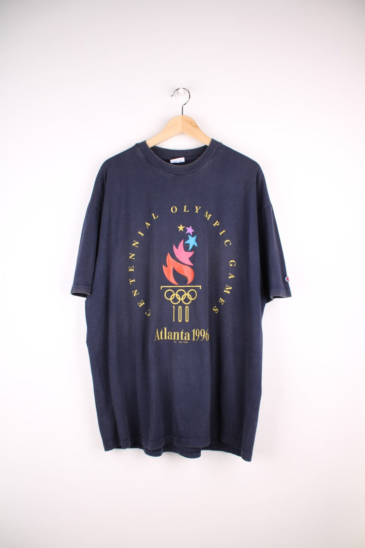 Champion 1996 Atlanta 'Centennial Olympic Games' t-shirt in navy blue with front graphic of Olympic torch, and small Champion C embroidered on the sleeve.