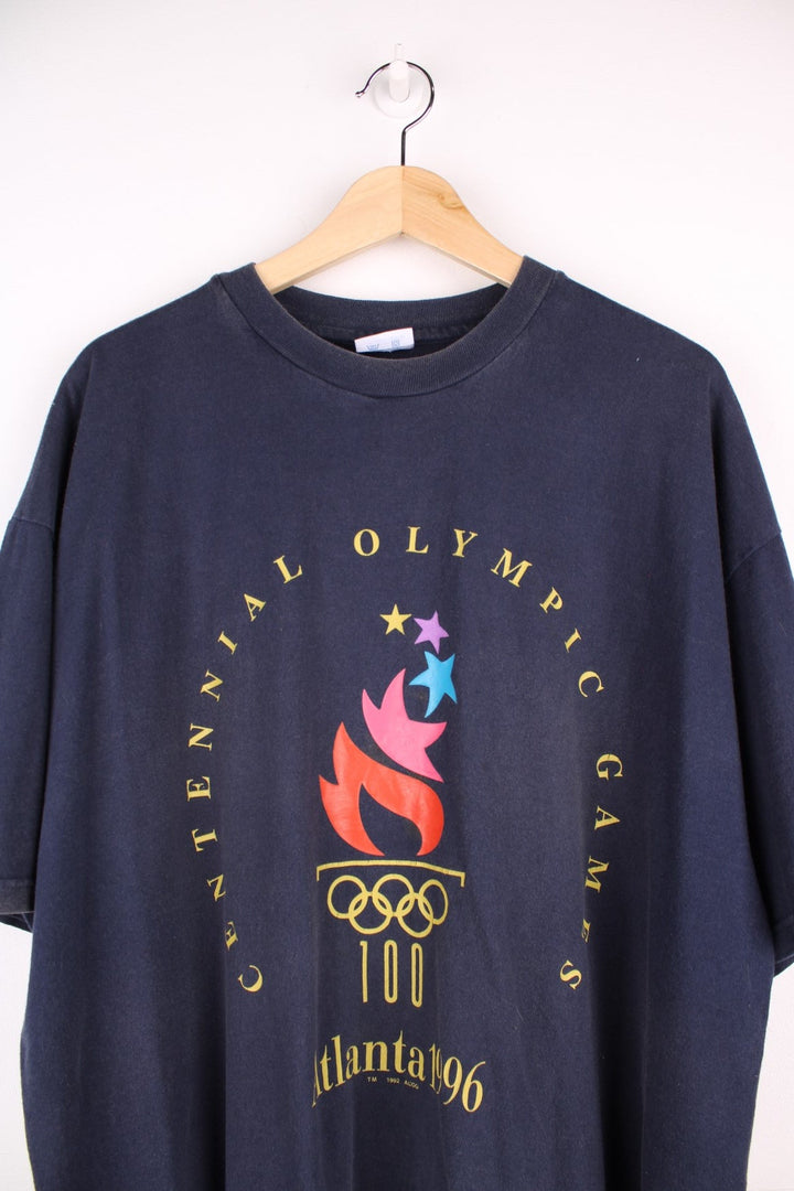 Champion 1996 Atlanta 'Centennial Olympic Games' t-shirt in navy blue with front graphic of Olympic torch, and small Champion C embroidered on the sleeve.