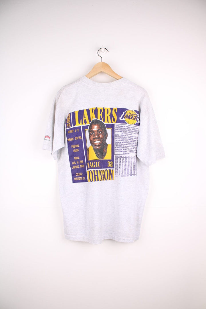 Los Angeles Lakers NBA Magic Johnson t-shirt in grey with yellow and purple accents, multiple team/NFL logos, illustrations of Johnson and his stats and a bio written on the back.