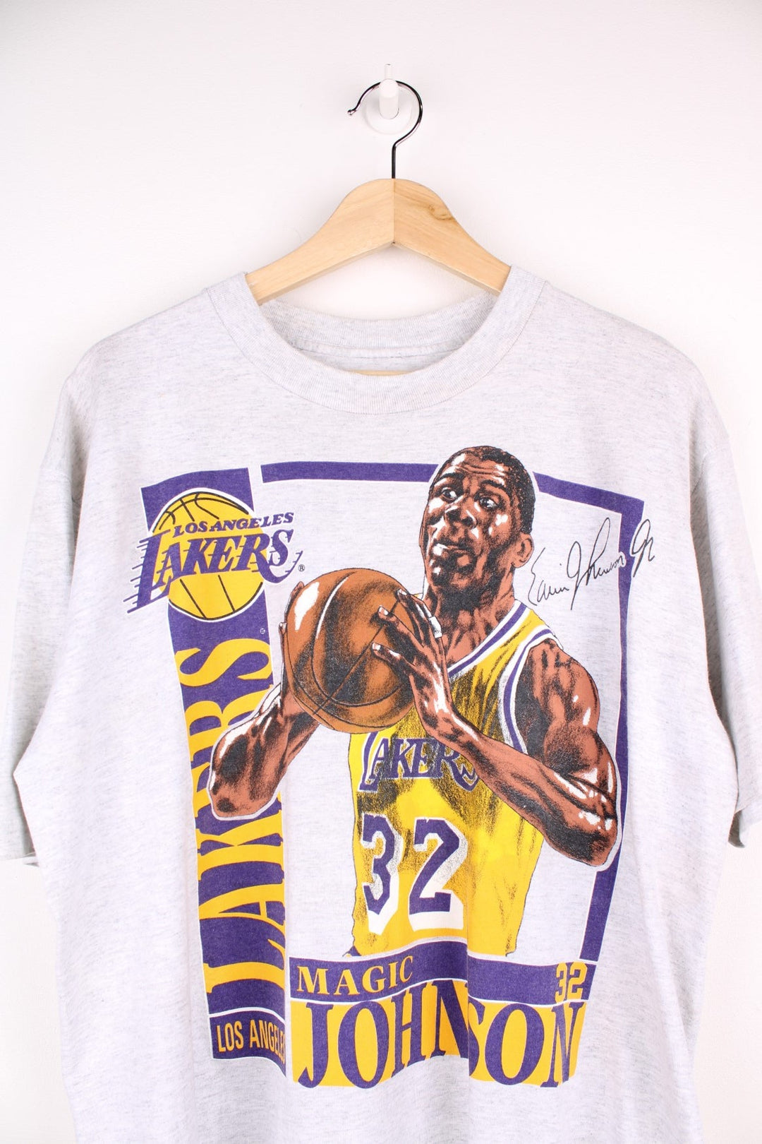 Los Angeles Lakers NBA Magic Johnson t-shirt in grey with yellow and purple accents, multiple team/NFL logos, illustrations of Johnson and his stats and a bio written on the back.