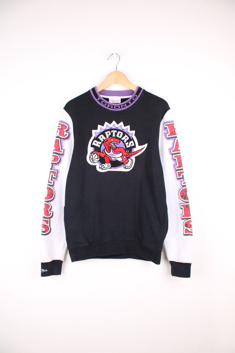 Mitchell & Ness Toronto Raptors Sweatshirt in a black, white, purple and red colourway with the logo embroidered on the front and the team spell out printed on the sleeves and collar, also has side pockets. 