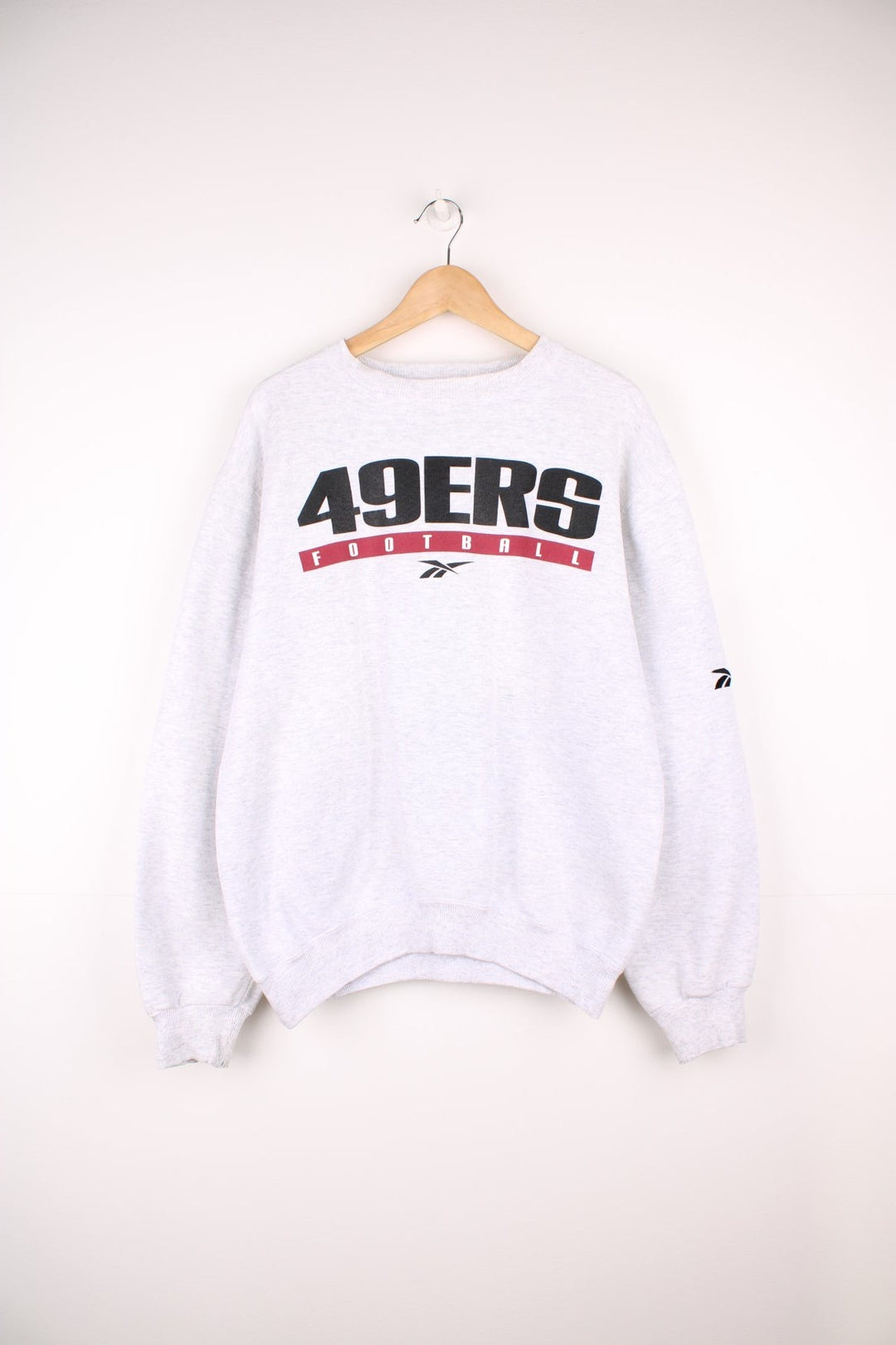 San Francisco 49ers Reebok Sweatshirt in a grey colourway with the team spell out and the Reebok logo printed across the chest.