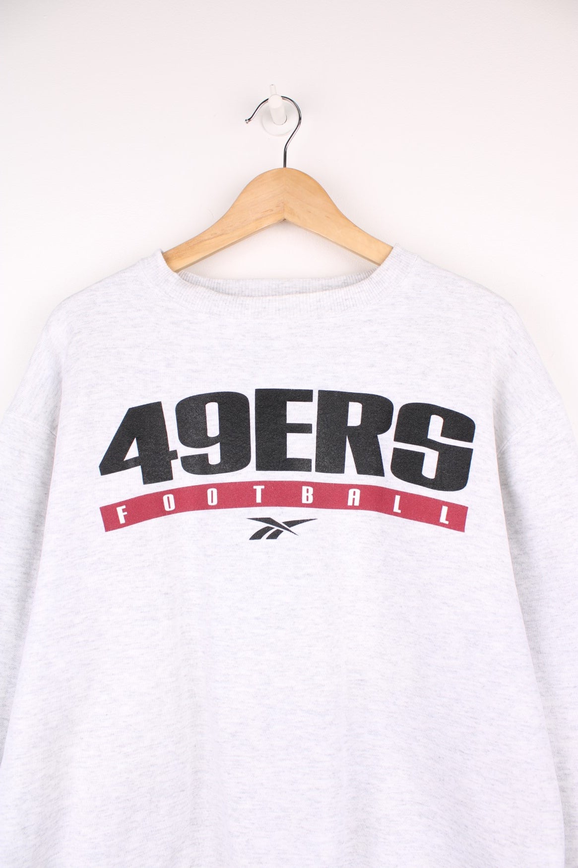 San Francisco 49ers Reebok Sweatshirt in a grey colourway with the team spell out and the Reebok logo printed across the chest.