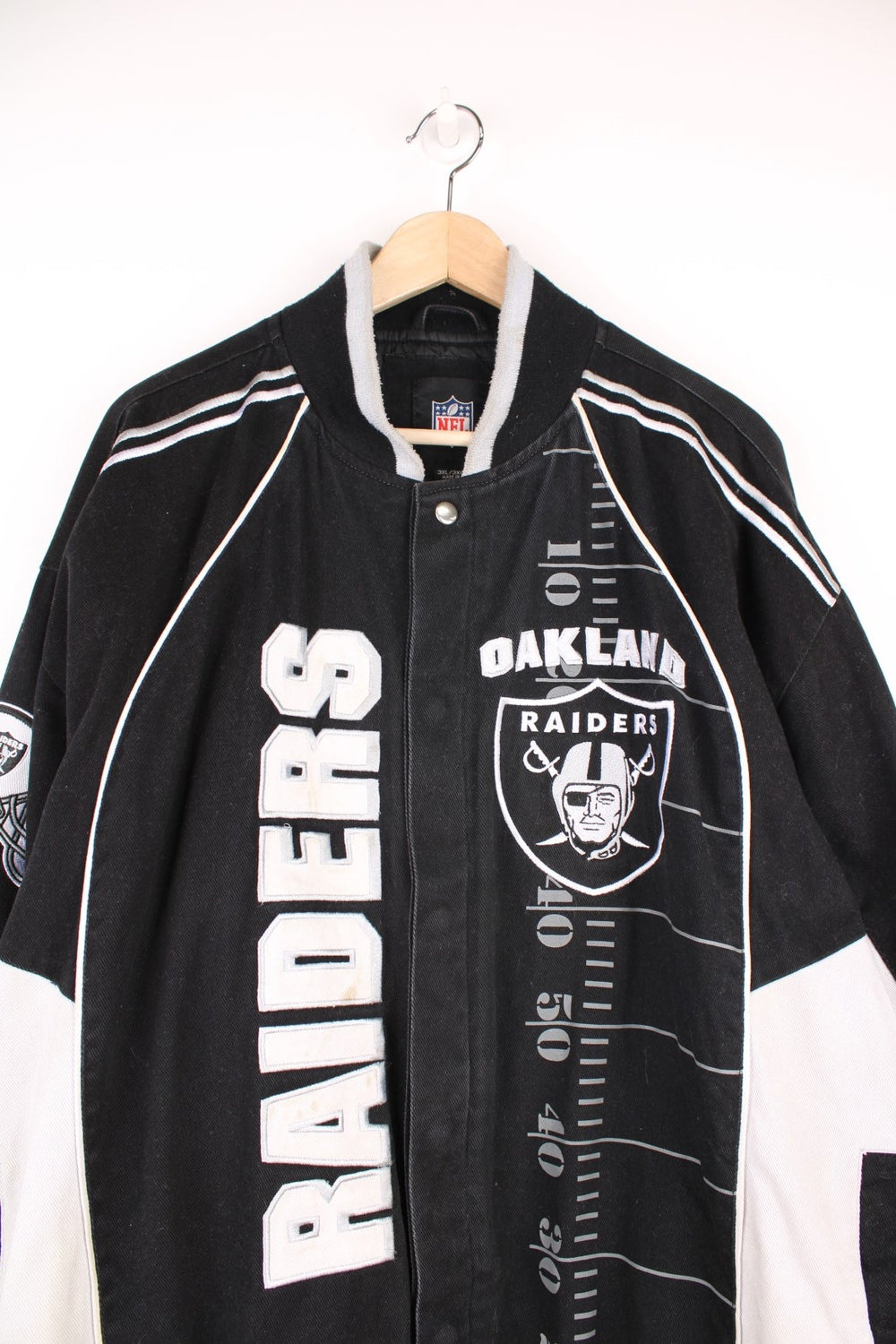 NFL Oakland Raiders jacket in black and white. Features embroidered badge on the front and back.