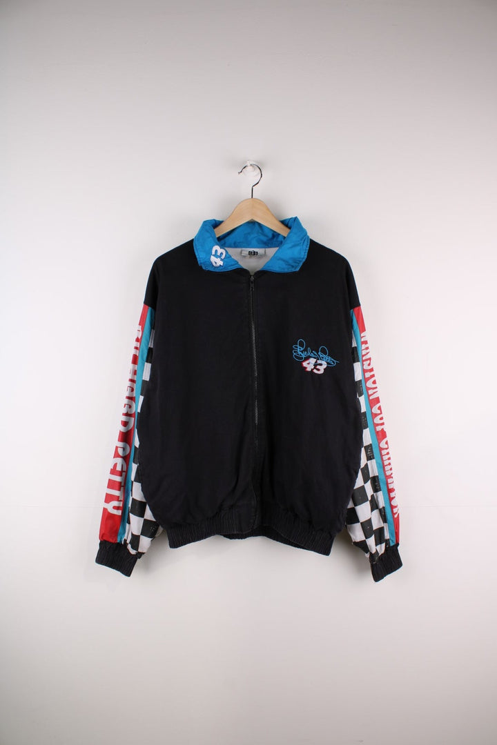 Vintage Richard Petty Nascar Racing Windbreaker in a black colourway with racing flag print going down the sleeve, alongside his name spell out down the sleeves, and his car and racing number 43 on the back.