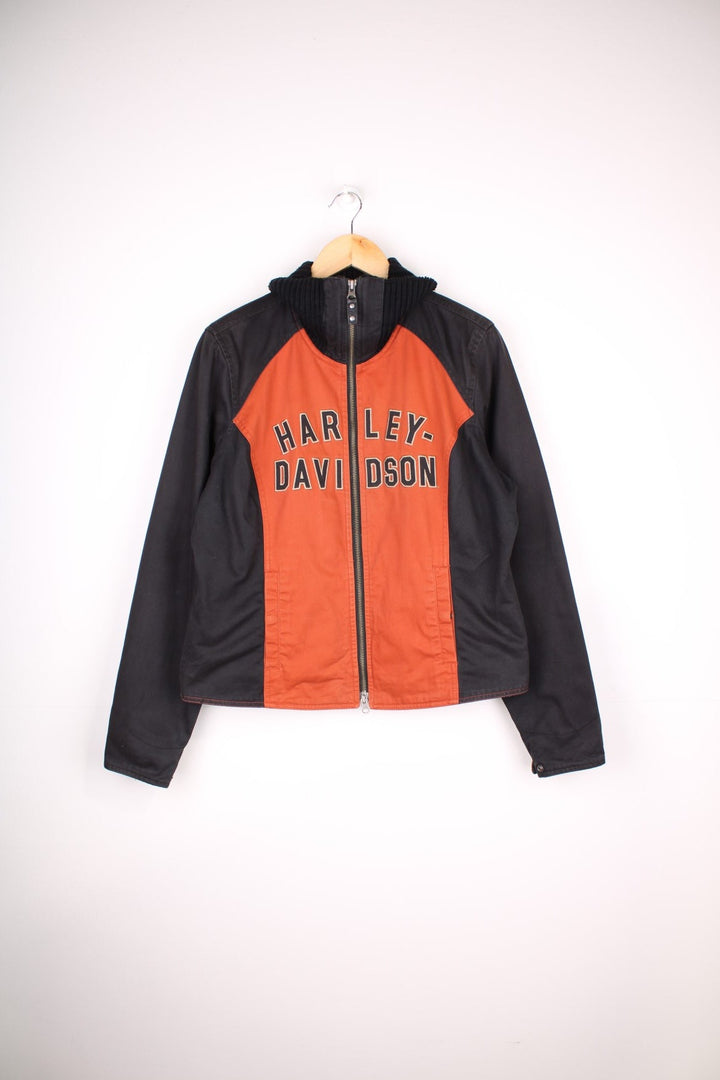 Harley-Davidson Jacket in a black and orange colourway, zips up and has a big collar, side pockets, and the spell out logo embroidered across the front.