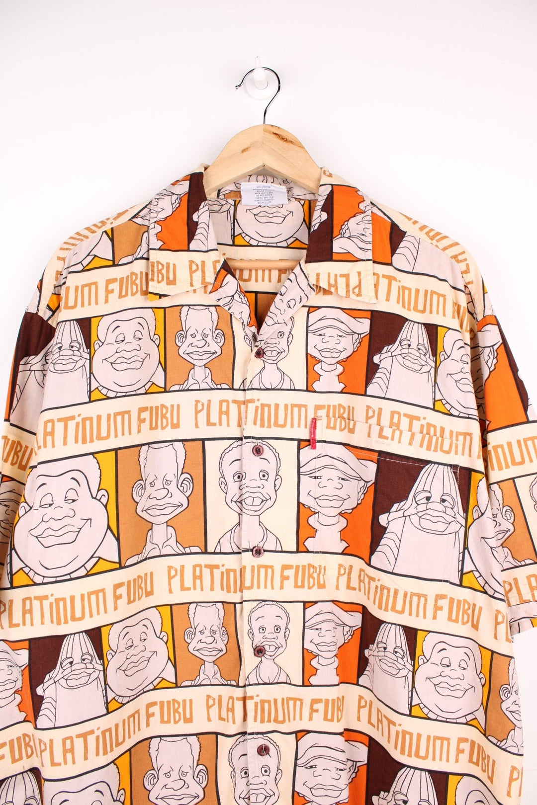 FUBU Platinum short-sleeved shirt in brown, orange and cream with cartoon print of Fat Albert and the Cosby Kids, button closure, one chest pocket, and a small logo tab in red.