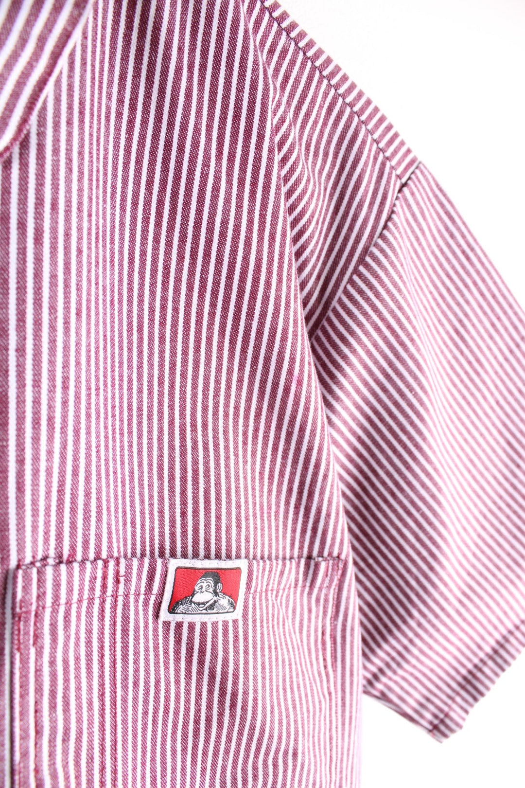 Ben Davis short-sleeved shirt in a red and white vertical stripe pattern with 1/2 zip closure, two breast pockets, and a small ape logo patch.