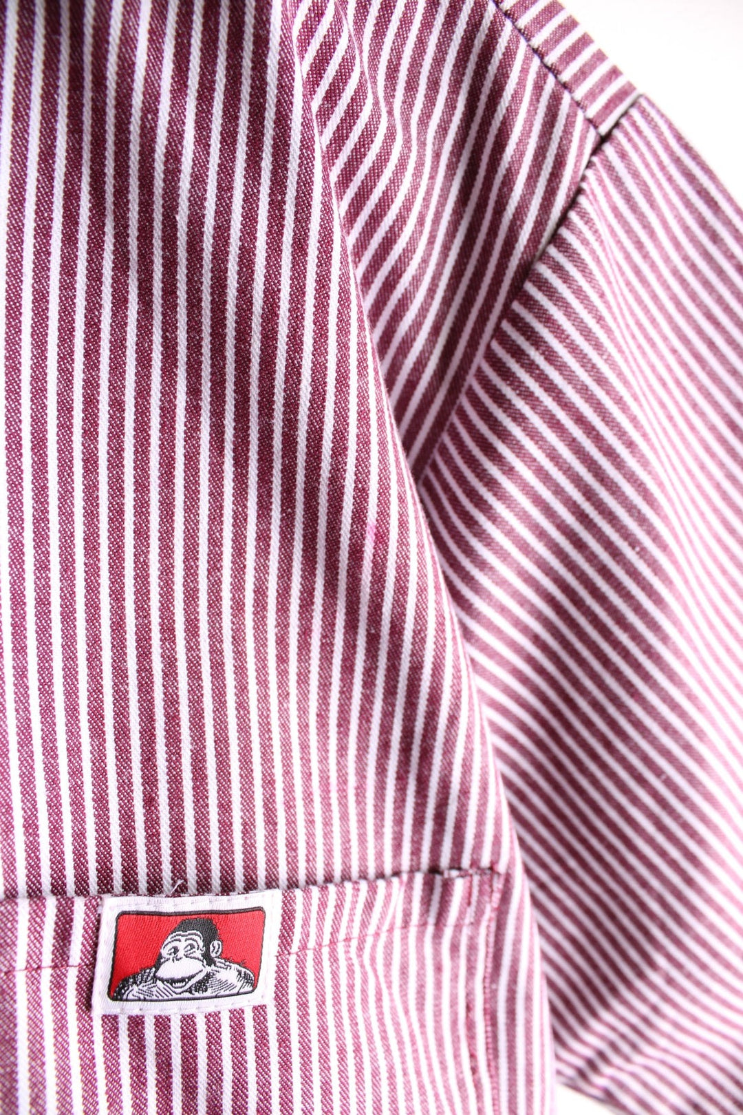 Ben Davis short-sleeved shirt in a red and white vertical stripe pattern with 1/2 zip closure, two breast pockets, and a small ape logo patch.